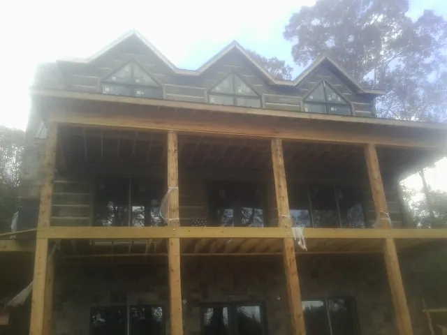 Dormers and porch framing on a large log home under construction — Roof Coating work by our crew in Port Washington