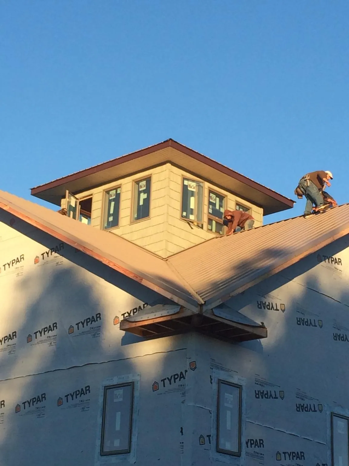 Roofers working around a rooftop cupola on a new metal roof at sunset — Roof Waterproofing in Port Washington by Roofing Brothers